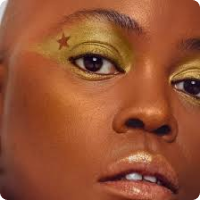 Woman with dark skin with gold eyeshadow with a star at the outside corner of her eye